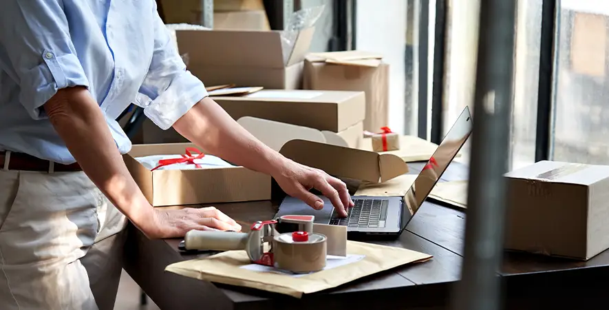 Online store small business owner packing shipping ecommerce boxes.