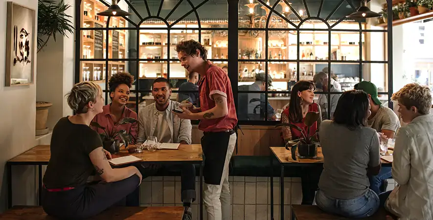 Waiter takes orders tableside with a POS system in a restaurant.