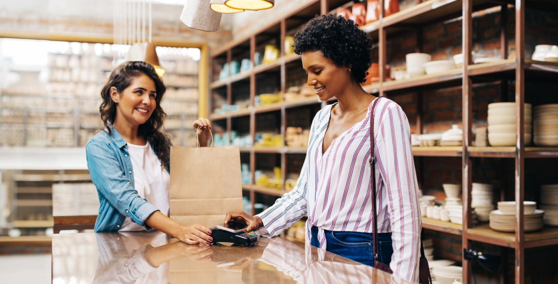 Customer and business owner interacting while doing a contactless transaction at retail store.