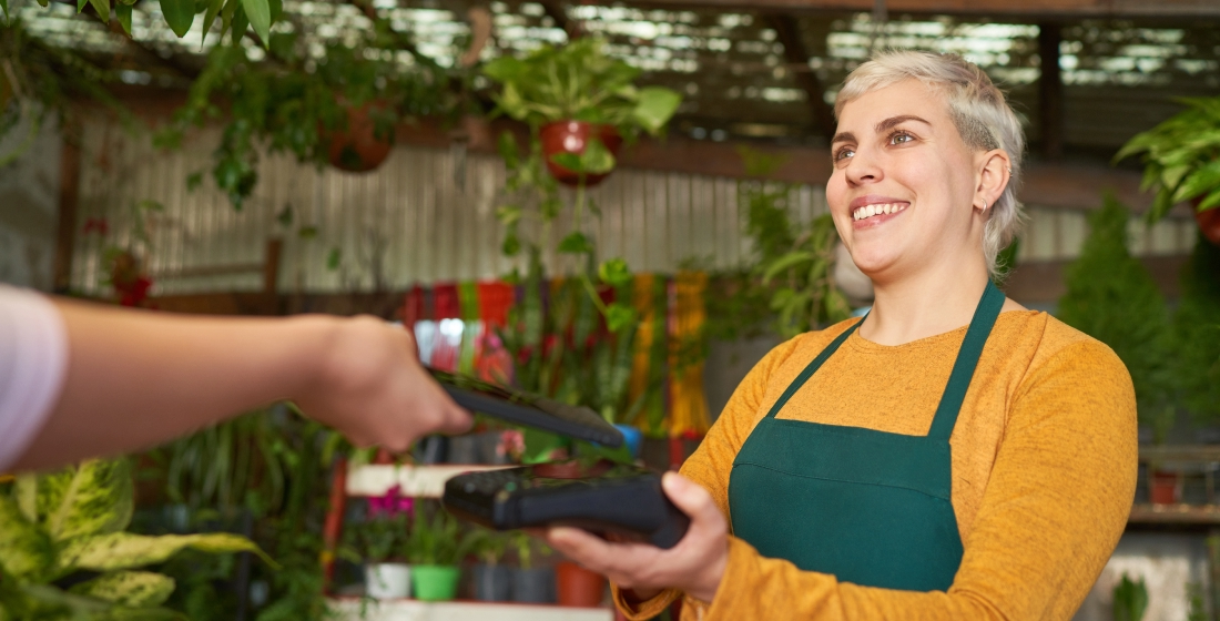 Merchant holding a payment terminal while receiving a contactless payment at fruit market