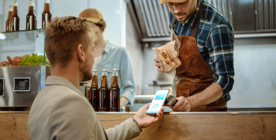 Customer tapping his mobile device to pay for order at food truck.