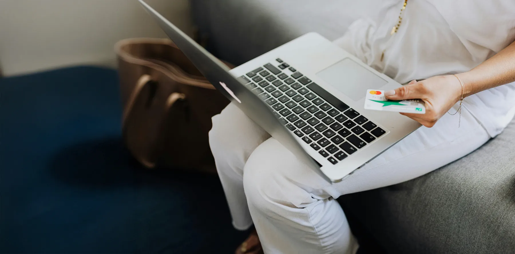 person using laptop and their credit card to make an online purchase