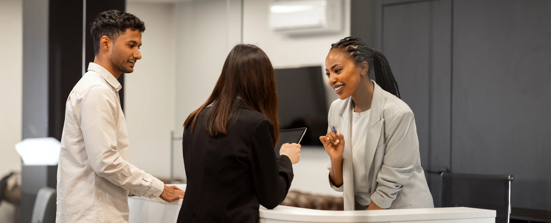 two customers at a counter talking to the administrator and setting up recurring billing on a tablet
