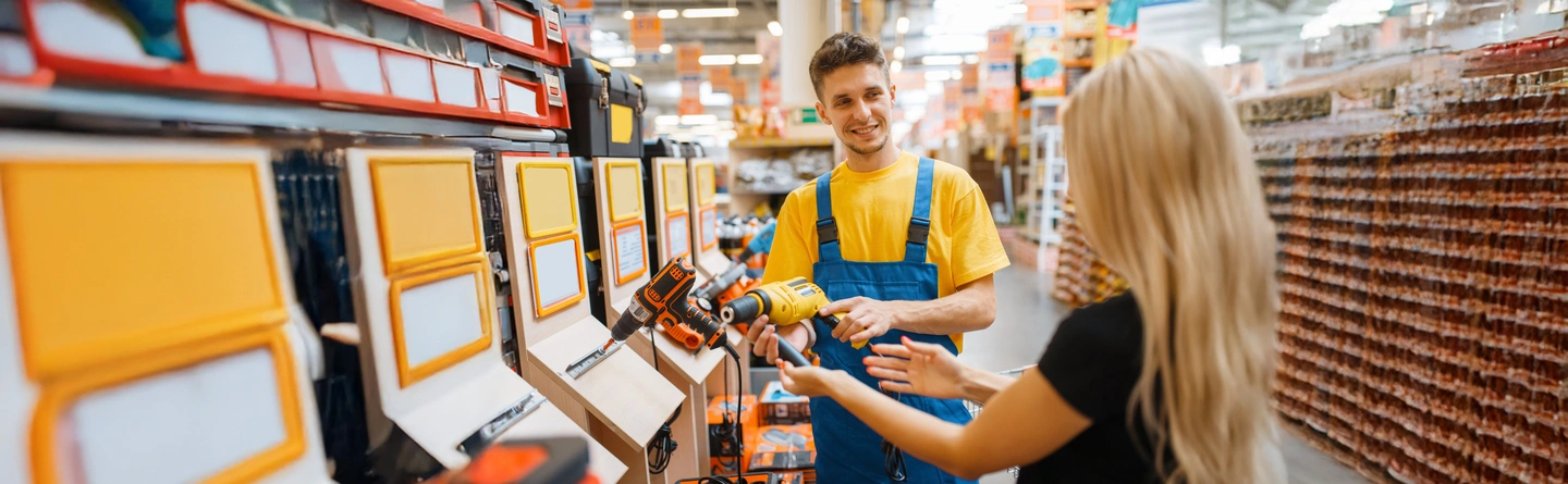 hardware store employee showing customer an impact drill and describing the difference from a regular drill
