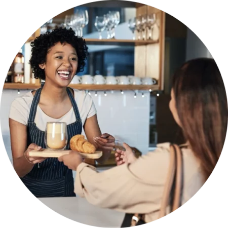 barista handing coffee and croissant order to a customer