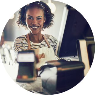 store employee at the POS smiling and holding out the handheld payment terminal so you can tap your credit card to pay