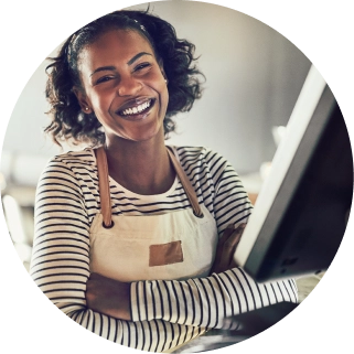 person wearing an apron standing at a POS terminal smiling at the camera
