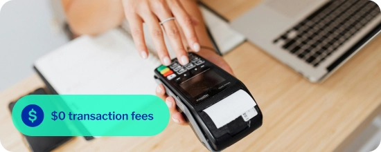 person holding and using a payment terminal, typing the total sale cost into the machine