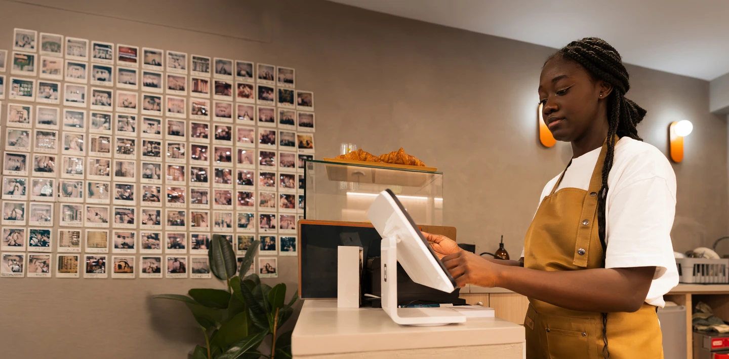 cafe employee standing at the counter using a touchscreen pos system