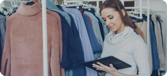 clothing store owner checking through inventory and inputting information on a tablet