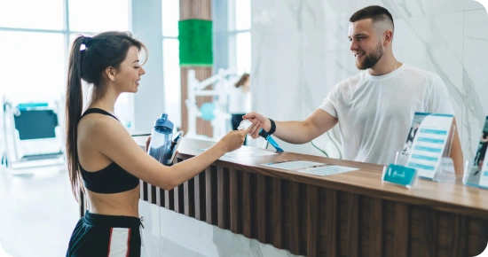 gym employee at the main counter scanning a gym users card for entry