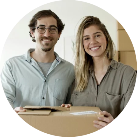 two business partners holding a cardboard box of inventory and smiling for the camera