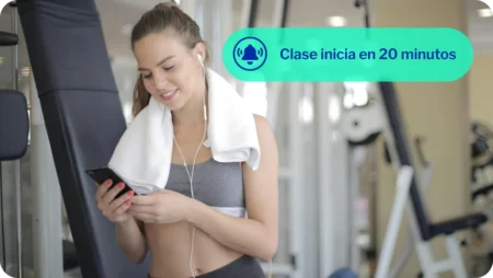 miembro de gimnasio recibiendo una notificación en su teléfono acerca de su clase que va a comenzar