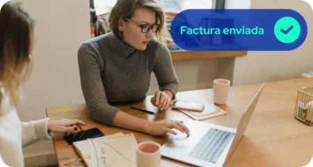 Dueña de negocio enviando facturas vía electrónica desde su laptop